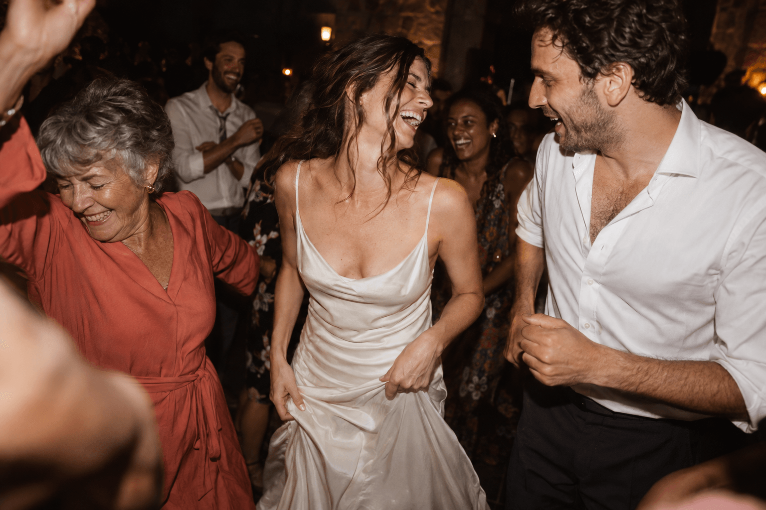 A bride, her partner and their loved ones dancing and laughing at the reception.